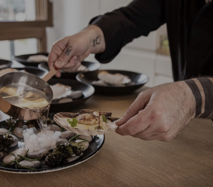 Photo du chef qui prépare une assiette de saint jacques